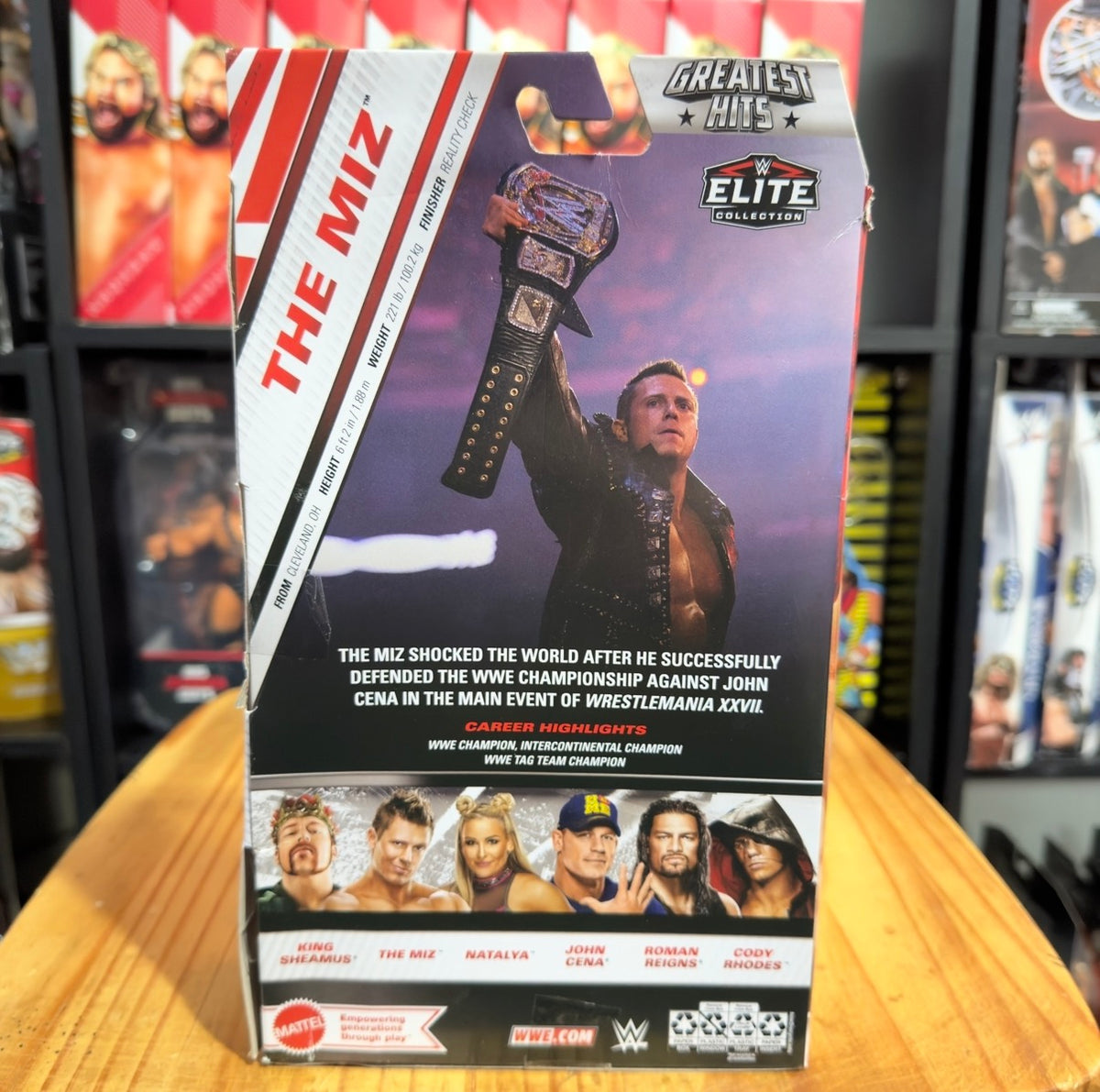 WWE Elite action figure box back panel with purple artwork and “Greatest Hits” badge.