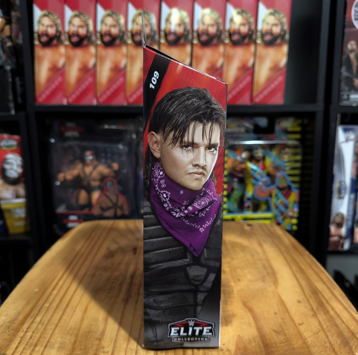 Boxed WWE action figure with black hair and purple bandana, front portrait view