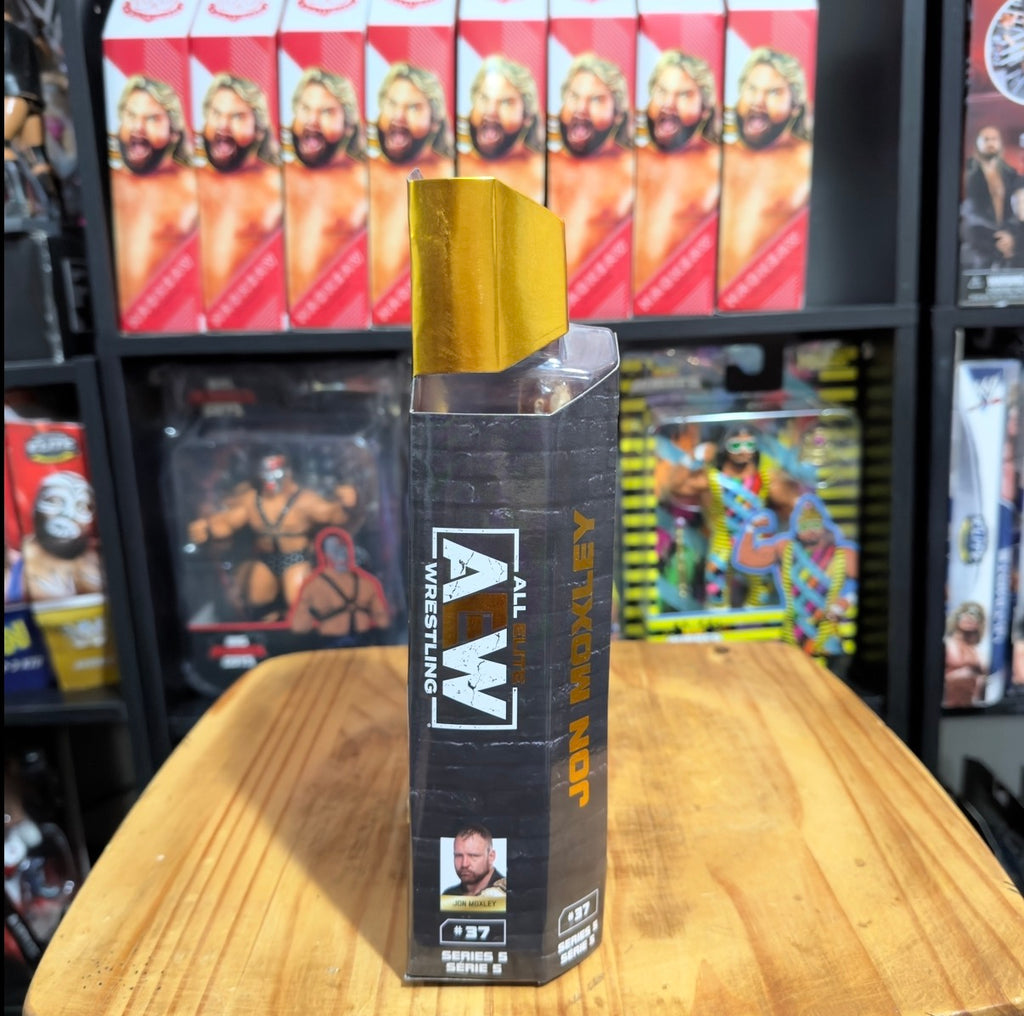 Wrestling action figure in box with gold top, AEW branding, and side label